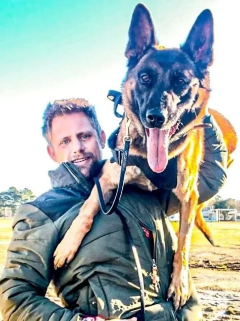 Dog trainer Cody Tallent holding a Belgian Malinois