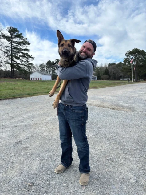Dog trainer Elliot holding his dog on a gravel road